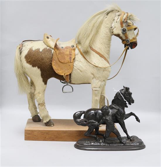 A model pony on wooden plinth with leather saddle and bridle and a spelter model of a horse with a young boy